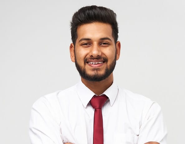 Portrait of young indian top manager in t-shirt and tie crossed arms and smiling on white isolated background